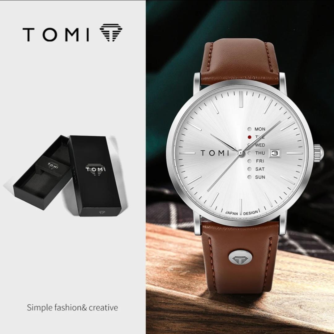 Montre TOMI à cadran blanc et bracelet en cuir marron avec son écrin noir, posée sur une table en bois